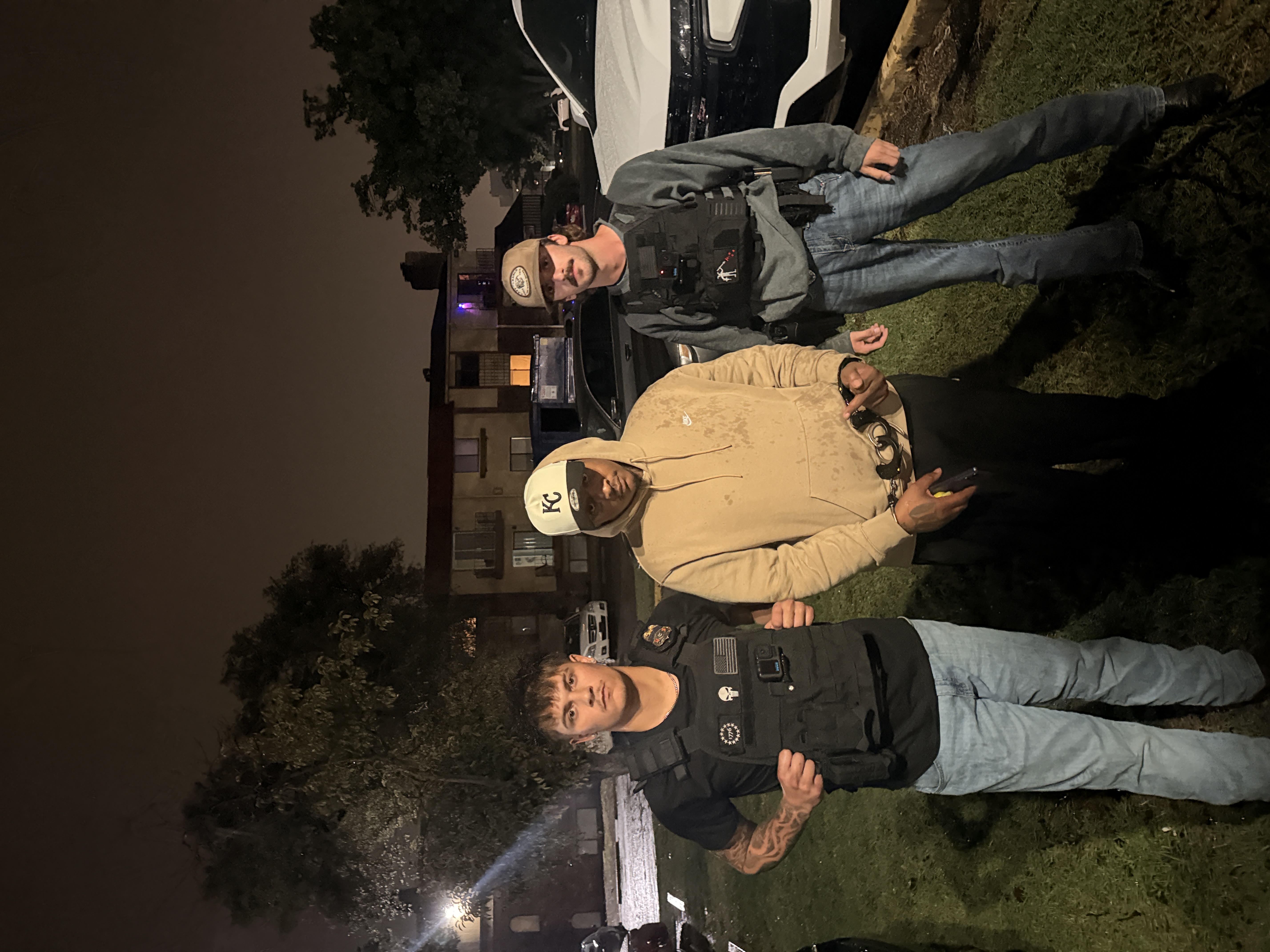 A group photographed outdoors beside a vehicle at night