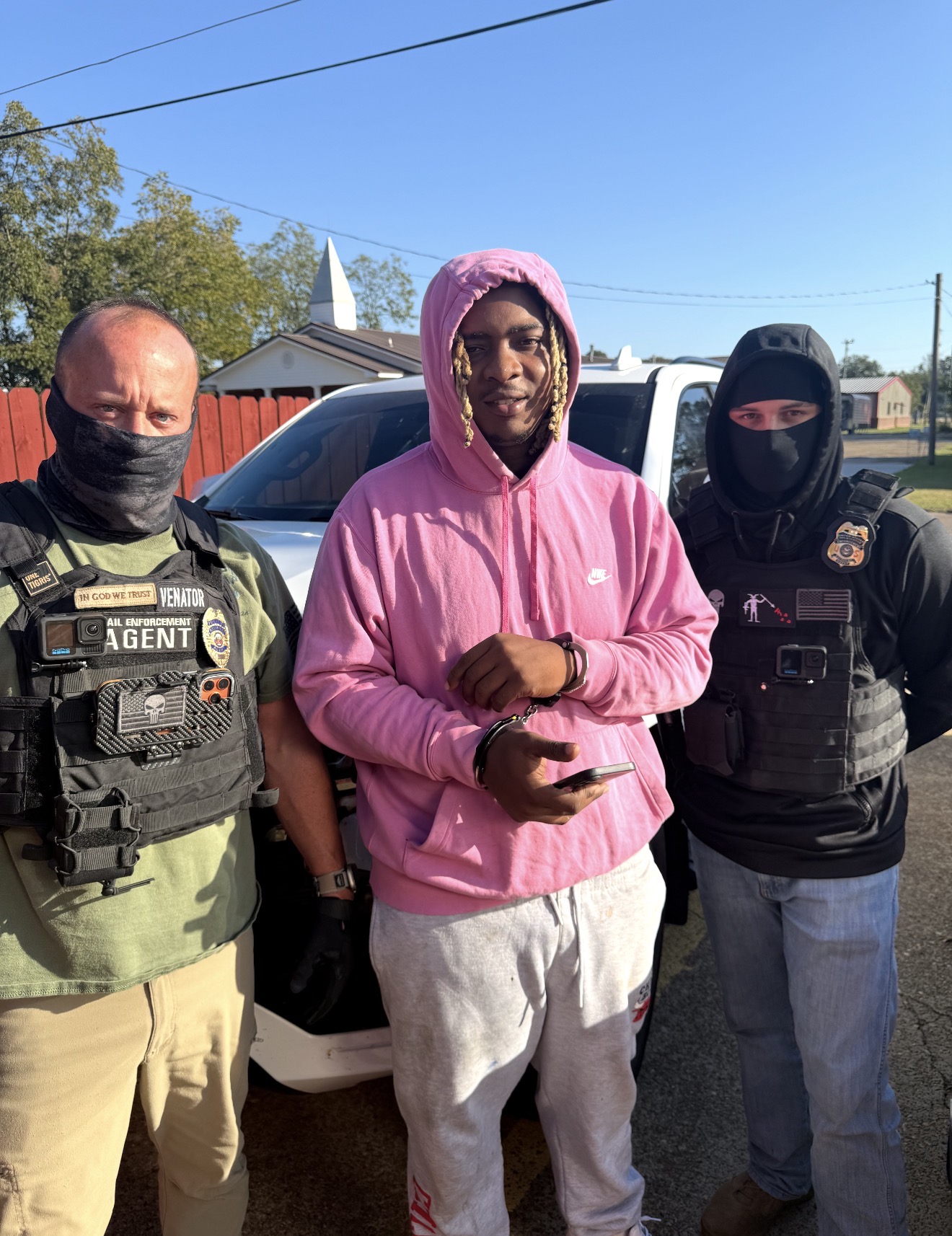 A group photographed beside a white vehicle outdoors
